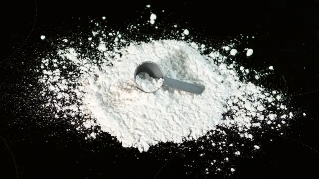 Dicas para ter uma alimentação saudável 10 Creatina com scoop sobre fundo preto.