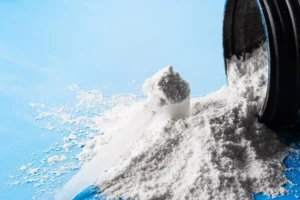 creatina monoidratada com scoop e um pote aberto sobre fundo azul. 