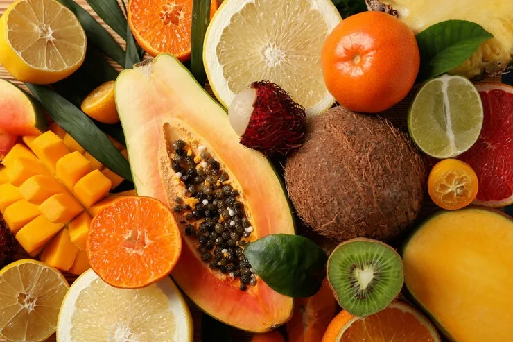 Dicas para ter uma alimentação saudável 8 A imagem apresenta uma seleção de frutas exóticas sobre uma superfície rústica de madeira, evidenciando alimentos naturalmente ricos em fibras. A ingestão adequada de fibras auxilia na digestão, no controle glicêmico e na saúde intestinal, promovendo uma alimentação equilibrada e funcional para o organismo.
