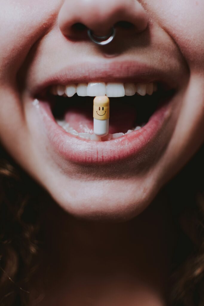 Mulher sorridente com uma pílula entre os dentes, enfatizando a busca por performance e bem-estar.