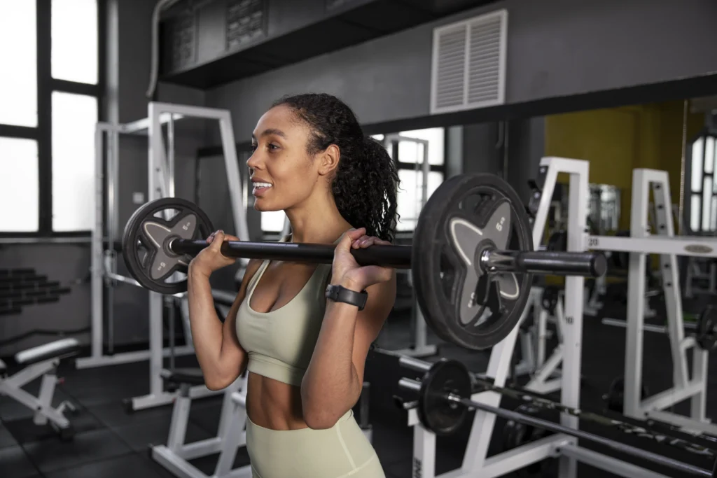 mulher realizando exercício físico com barra livre em academia.