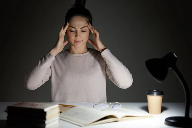 Como cuidar da saúde mental: jovem sentada em mesa de trabalho realizando exercício de respiração