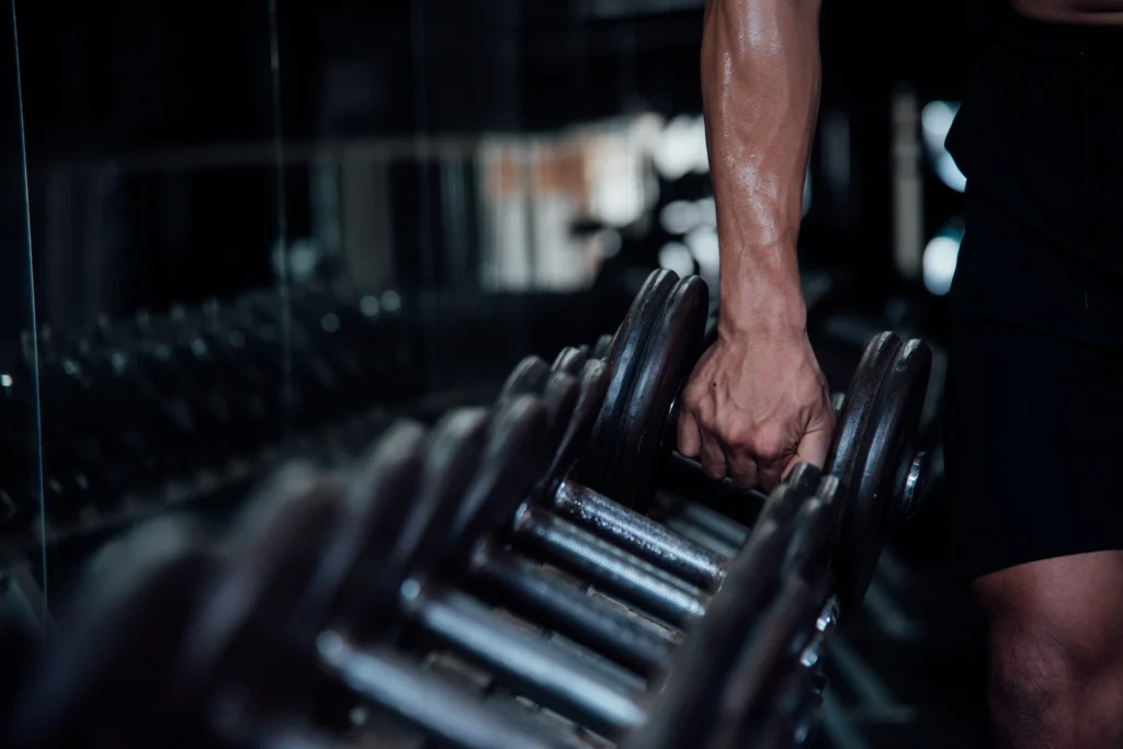 Homem jovem em roupa de ginástica durante exercício em uma aula de academia, buscando alta performance.