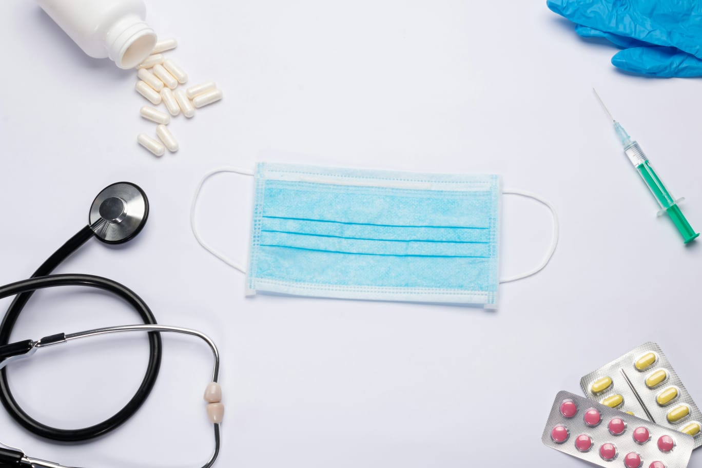 Máscara, estetoscópio e remédios sobre a mesa ilustrando a diferença entre gripe e resfriado.