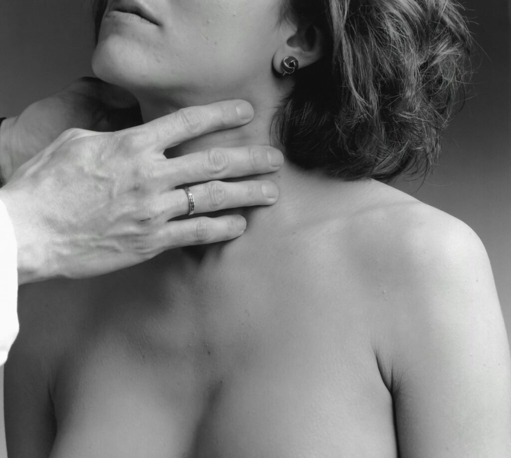 Profissional de saúde examinando a região da tireoide de uma paciente, essencial para diagnosticar disfunções hormonais.