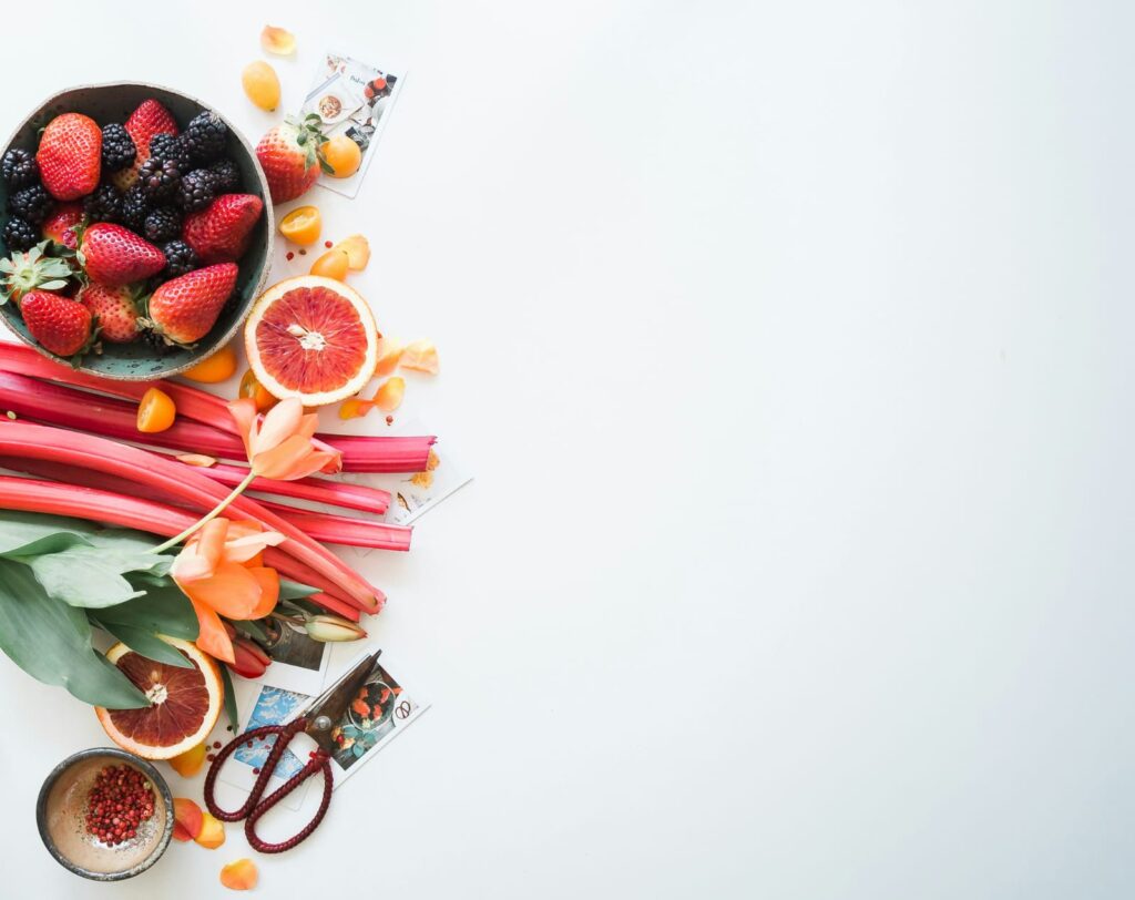 Alimentos saudáveis como frutas, grãos e vegetais dispostos em fundo branco, reforçando a importância da alimentação e saúde mental.