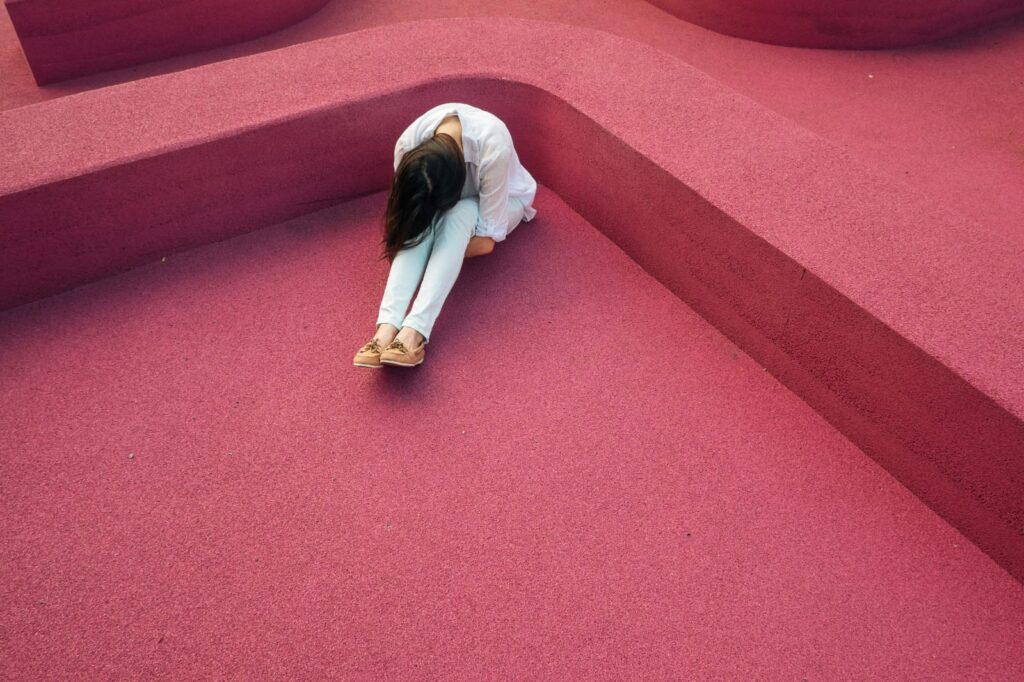 Pessoa sentada abraçando as pernas, expressando sentimentos comuns relacionados ao estigma e transtorno mental.