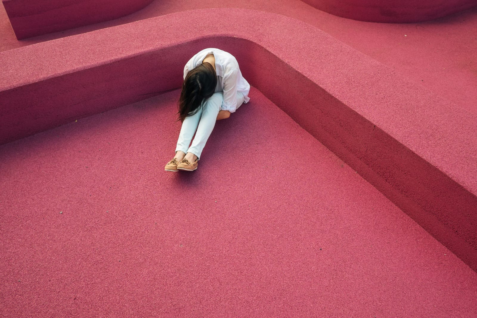 Pessoa sentada abraçando as pernas, expressando sentimentos comuns relacionados ao estigma e transtorno mental.