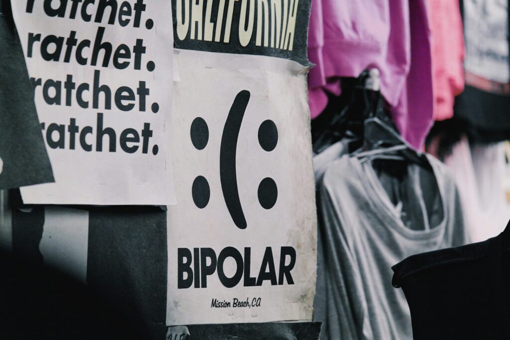 Cartazes colados em uma parede, com destaque para um que exibe a palavra “bipolar”