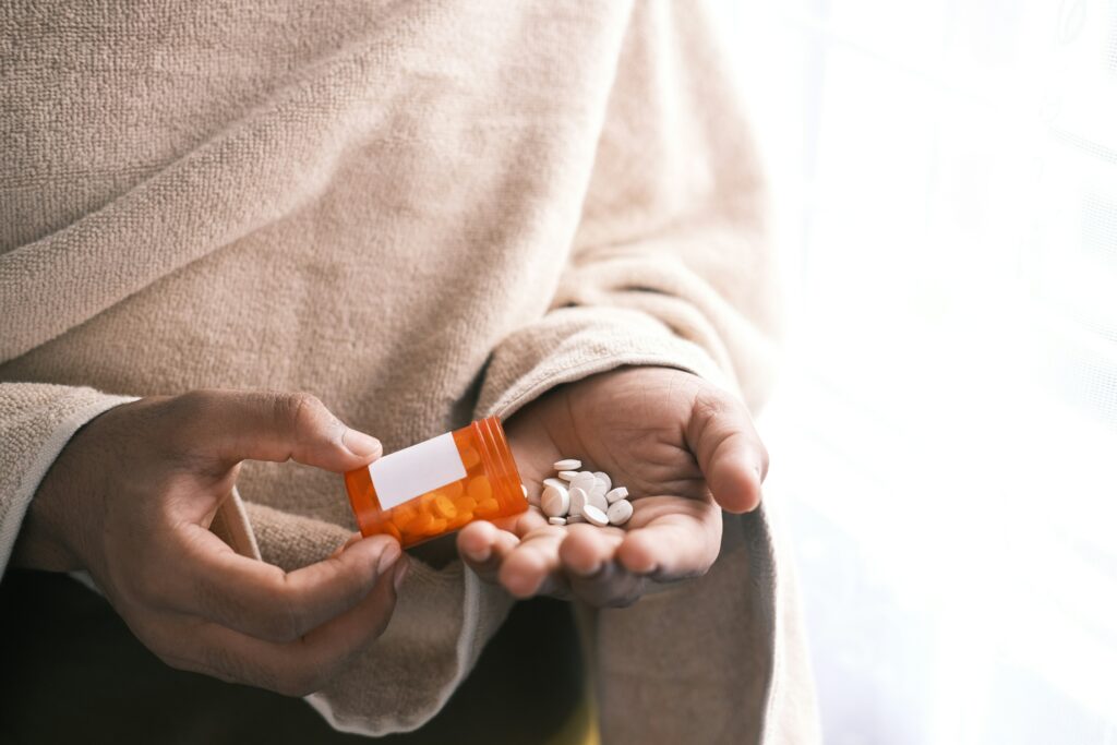 Pessoa segurando medicamentos na palma da mão.