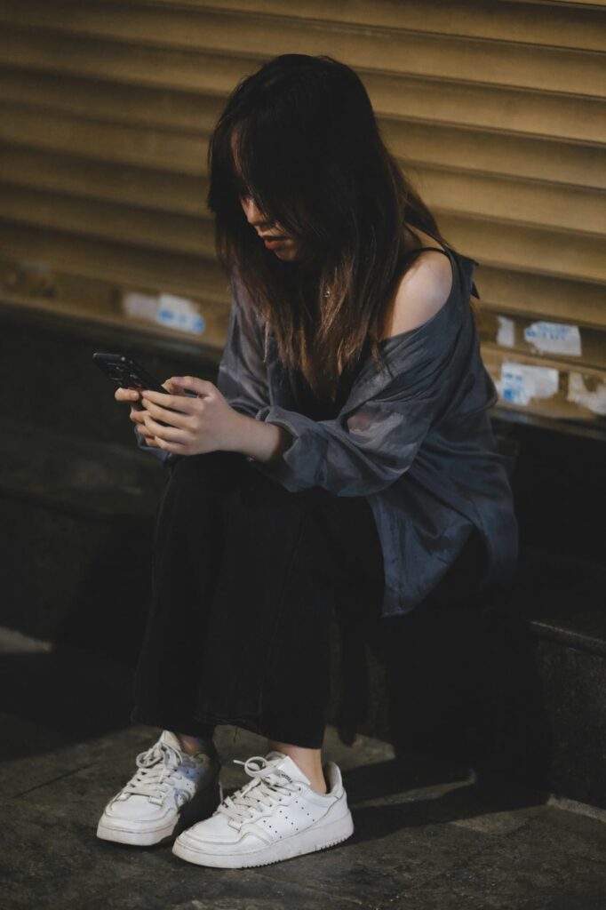 Mulher sentada olhando o celular em momento de pausa e reflexão - dicas de saúde mental.