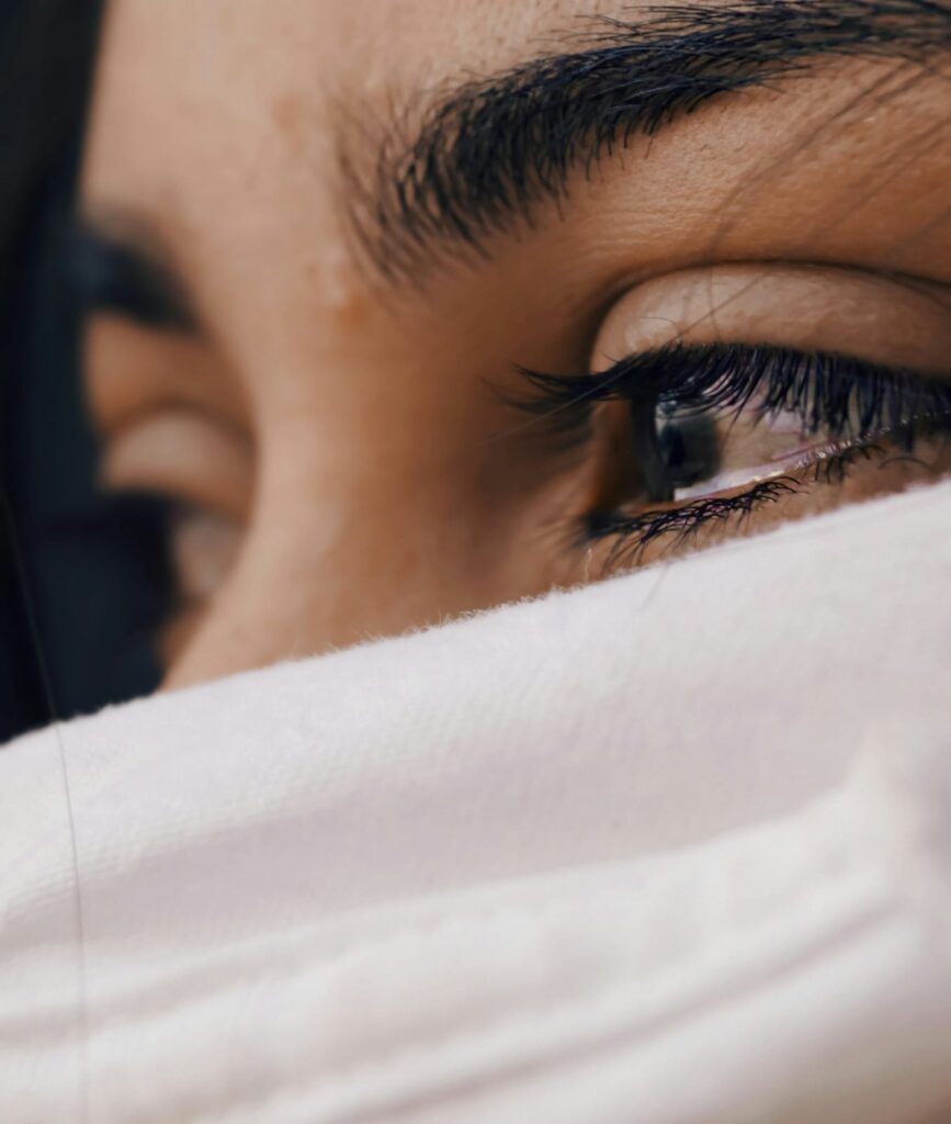 Olhos cheios de lágrimas, expressando sofrimento emocional intenso devido ao diagnóstico de doenças autoimunes.