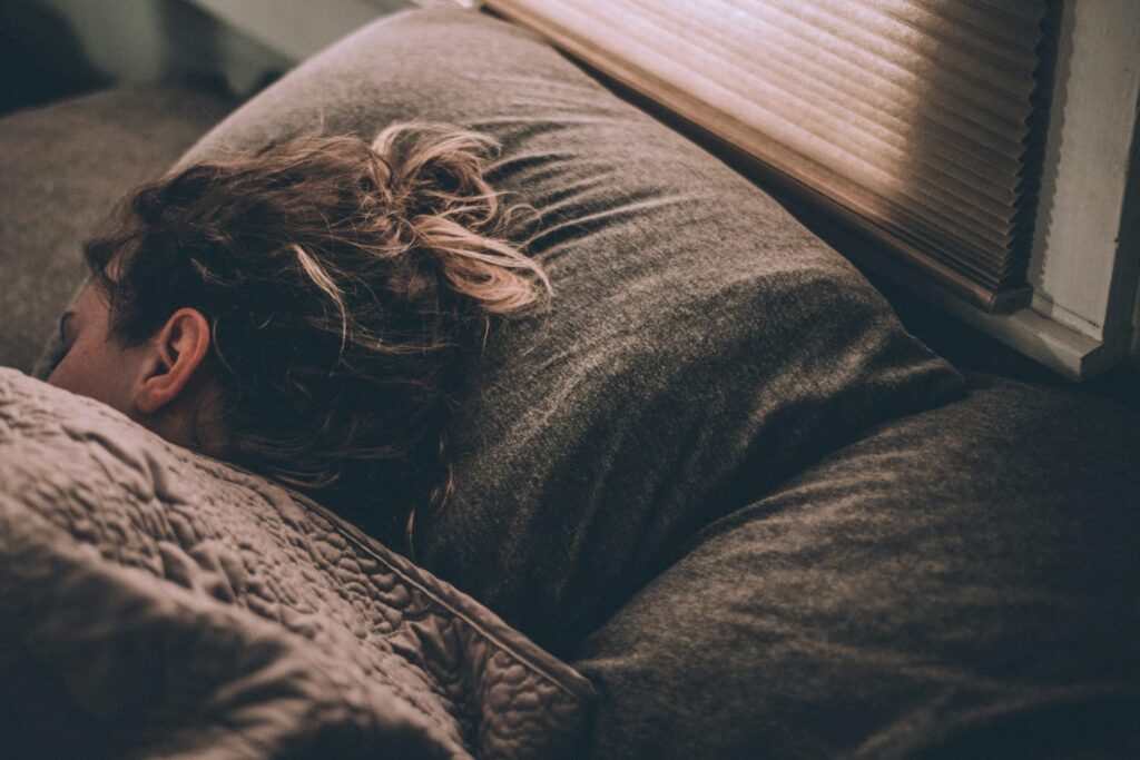 Mulher dormindo tranquilamente em uma cama com expressão serena.