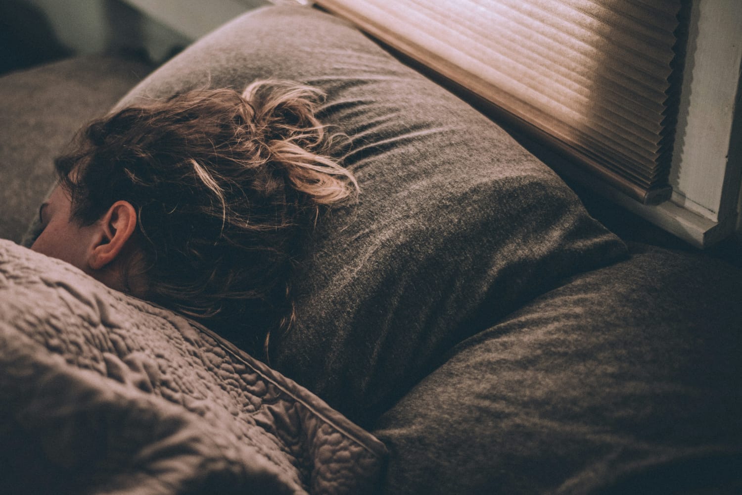 Mulher dormindo tranquilamente em uma cama com expressão serena.