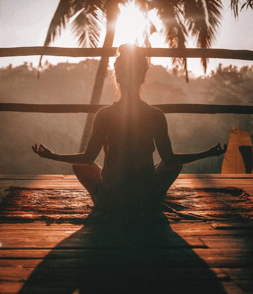 Pessoa praticando meditação com as pernas cruzadas em ambiente calmo.