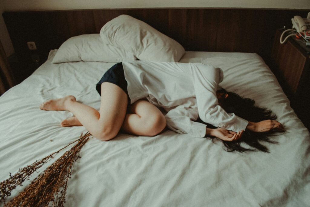 Mulher deitada segurando a cabeça com expressão de desconforto, comuns na intolerância à lactose.