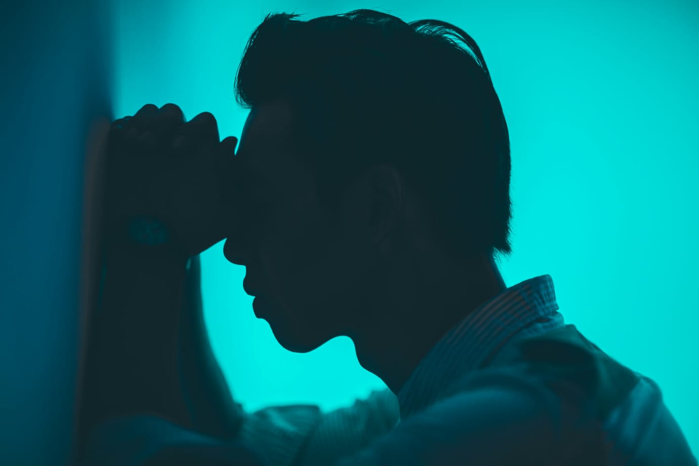 Homem com expressão de cansaço, mãos fechadas na testa, aparentando dificuldade de concentração.