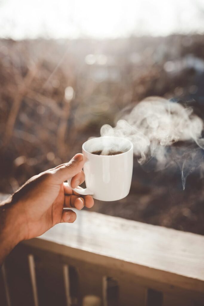 Imagem mostra uma mão segurando uma xícara de café, remetendo ao consumo da substância e ao questionamento comum: cafeína emagrece?