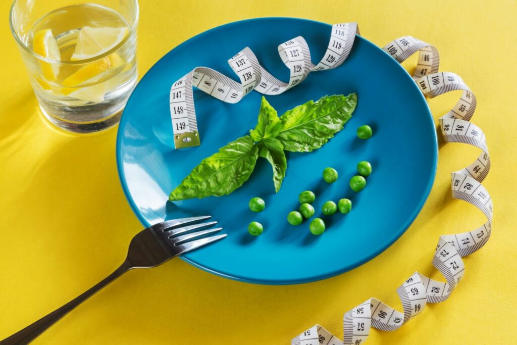 Prato com pouca comida e fita métrica, retratando as mudanças alimentares que são a chave do tratamento da obesidade. Essa estratégia muitas vezes é usada em associação com medicamentos como o orlistate.