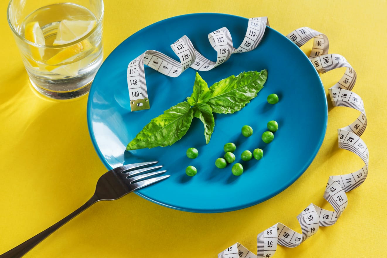 Prato com pouca comida e fita métrica, retratando as mudanças alimentares que são a chave do tratamento da obesidade. Essa estratégia muitas vezes é usada em associação com medicamentos como o orlistate.