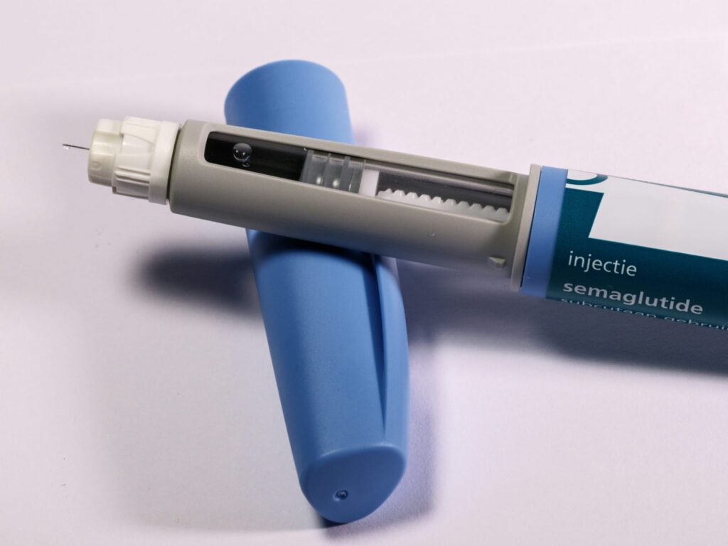 Caneta de Ozempic aberta com agulha exposta, usada no tratamento da obesidade.