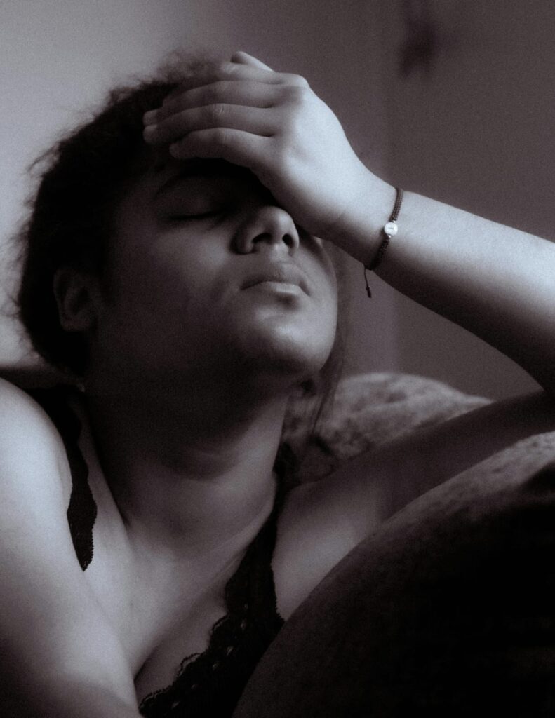 Mulher com expressão de desconforto e a mão na testa, simbolizando os efeitos físicos da fibromialgia.