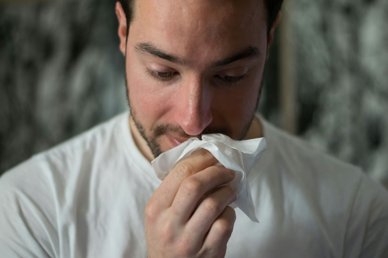 Homem com nariz entupido usando lenço de papel, ilustrando dúvida sobre se descongestionante nasal faz mal.