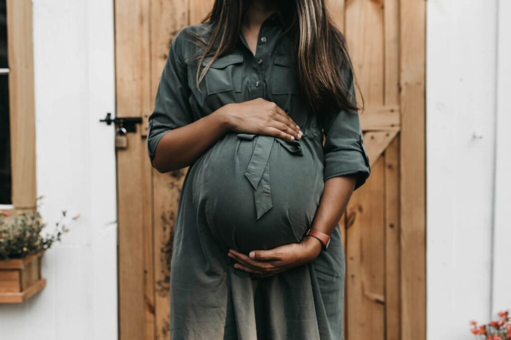 Mulher grávida com as mãos sobre a barriga, simbolizando cuidado e atenção durante o uso de medicamentos na gravidez.