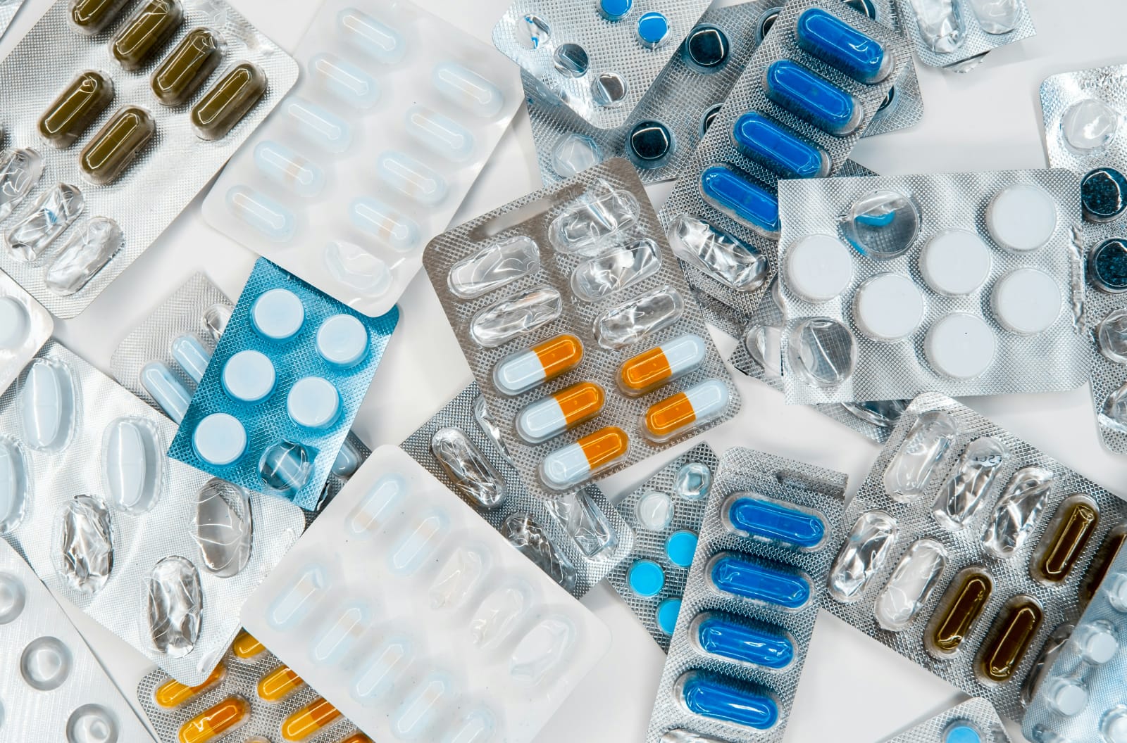 Diversos comprimidos e cápsulas em blisters, representando os possíveis tratamentos para o nervo ciático inflamado.