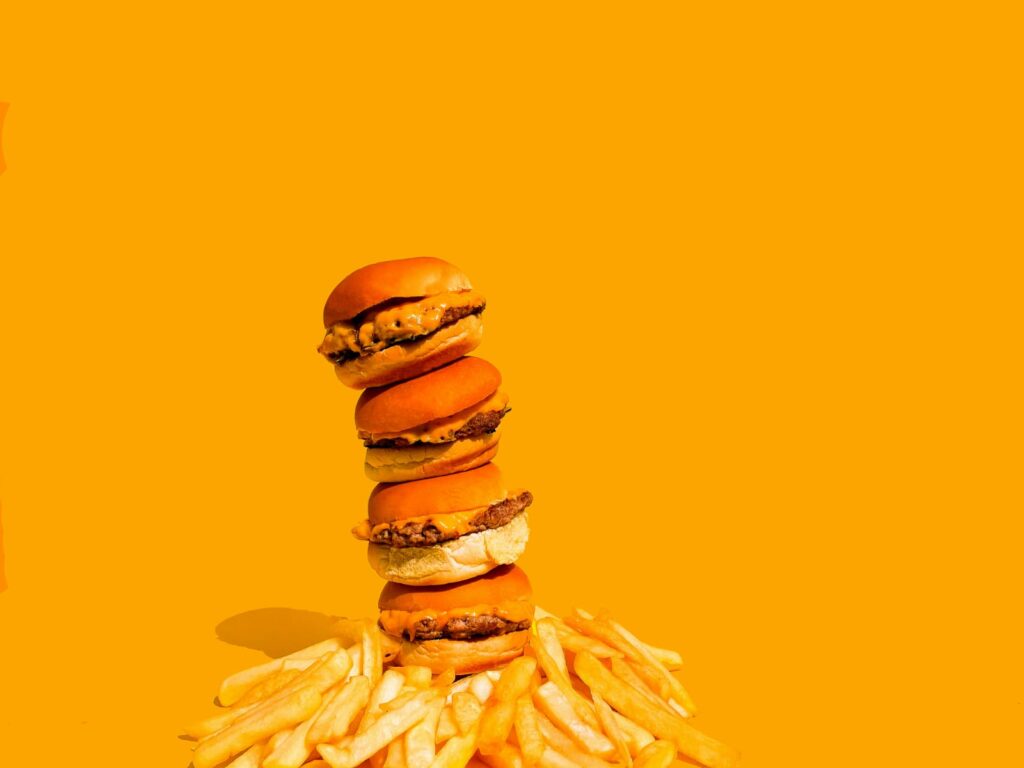 Hambúrgueres e batatas fritas simbolizando alimentos que aumentam o colesterol LDL.