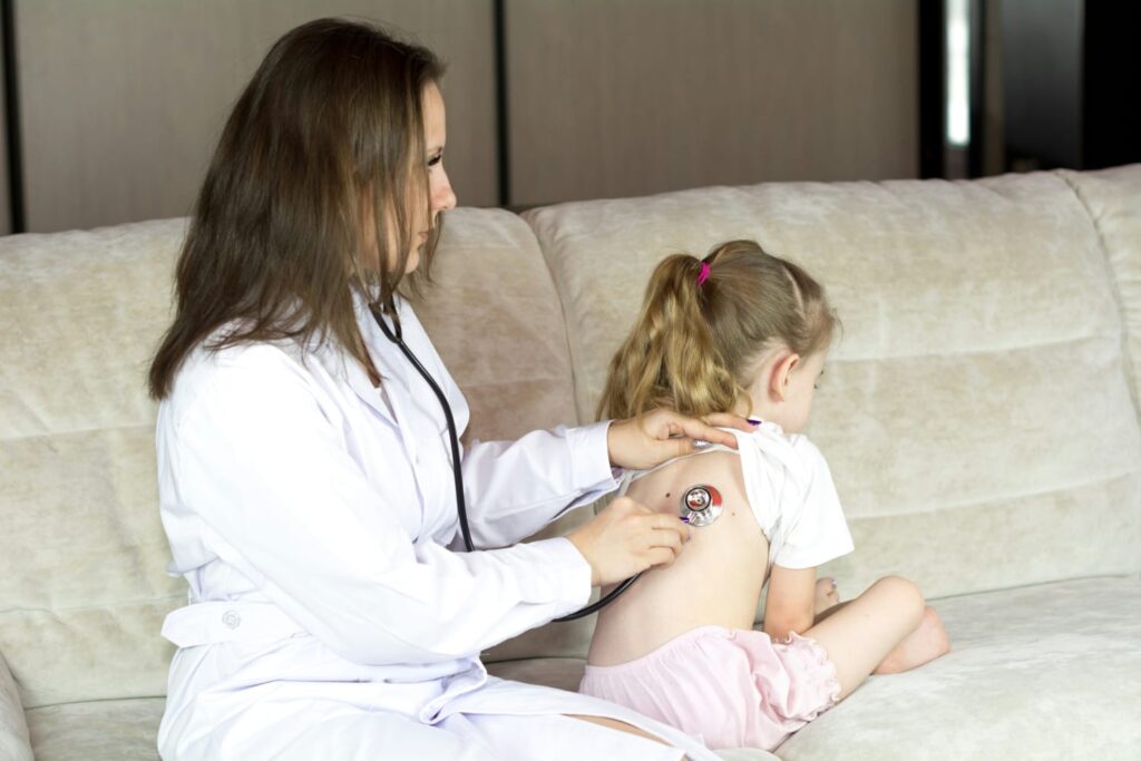 Médica examinando criança com estetoscópio durante acompanhamento da cardiopatia congênita.