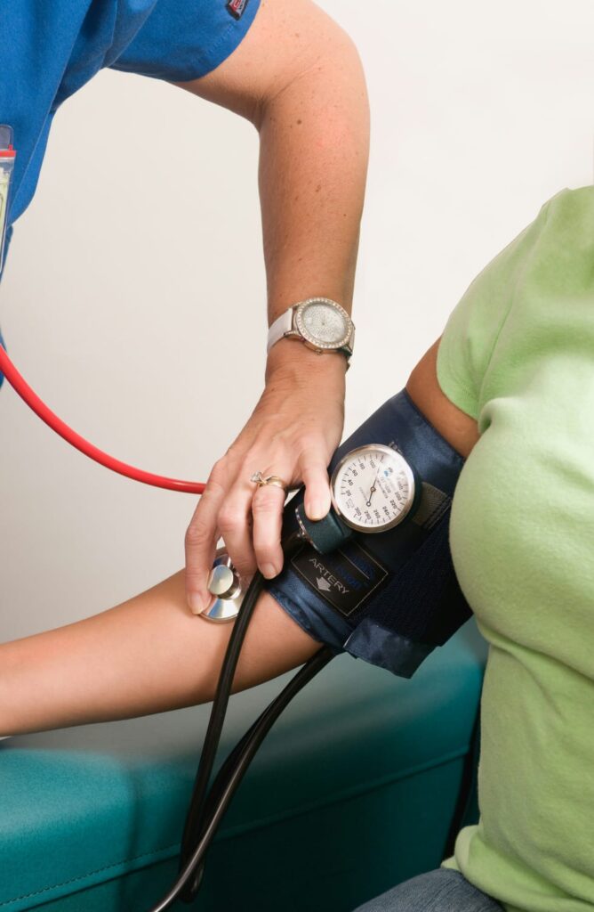 Profissional de saúde aferindo a pressão arterial de um paciente com esfigmomanômetro.
