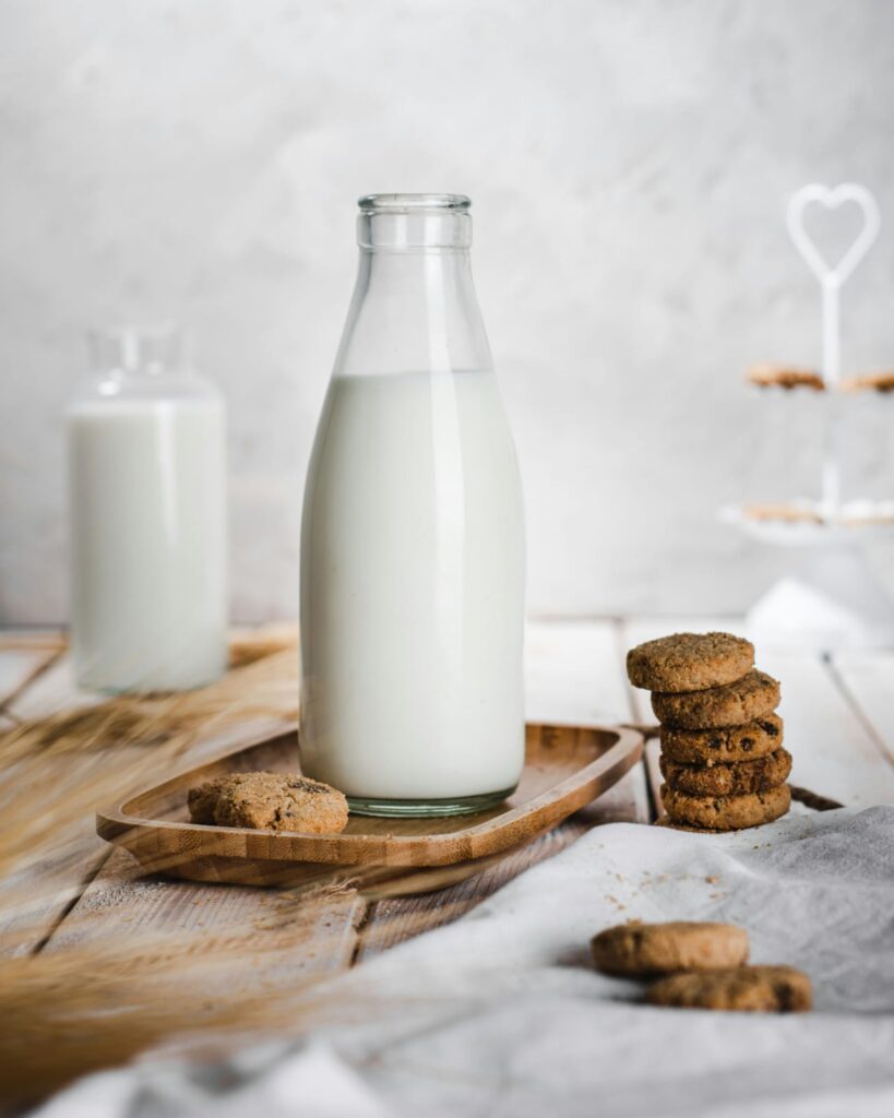 Leite em garrafa de vidro acompanhado de biscoitos, alimento associado à intolerância à lactose.