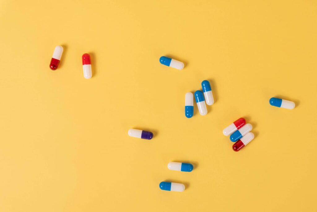 Cápsulas de medicamentos em fundo amarelo, sugerindo tratamento para a narcolepsia.