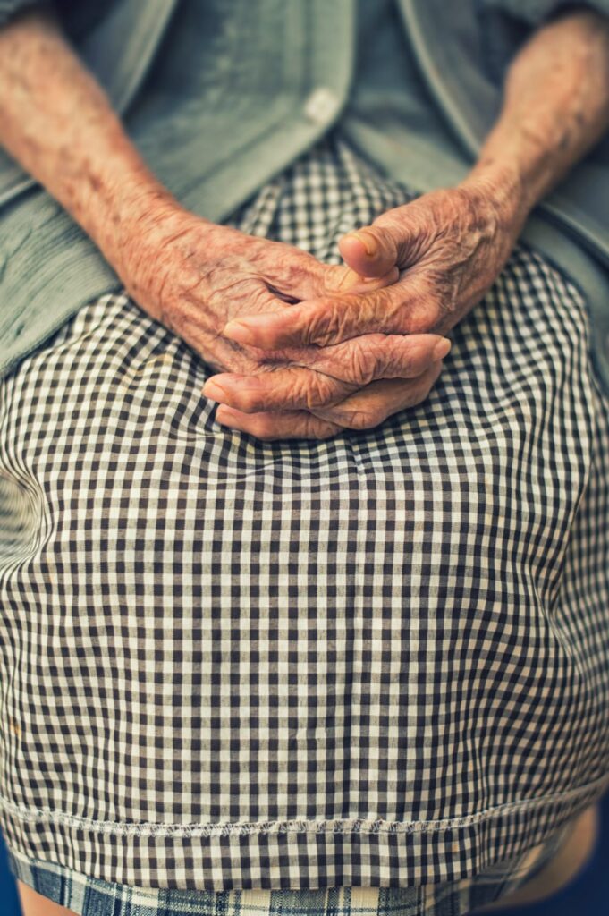 Mãos envelhecidas apoiadas no colo, representando fragilidade causada pela sarcopenia.