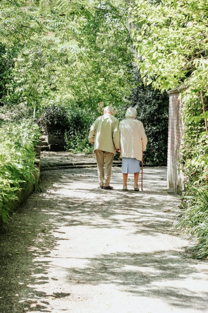 Idosos caminhando juntos em parque arborizado, simbolizando os desafios e cuidados da sarcopenia.