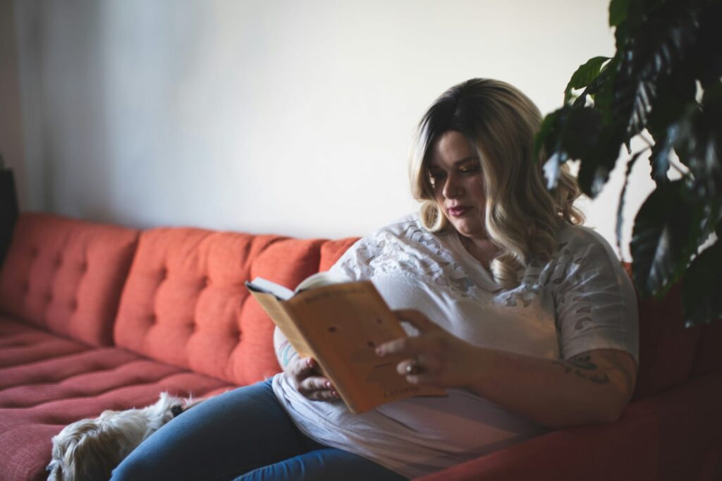 Mulher sentada no sofá lendo livro, em referência ao uso de sibutramina no tratamento da obesidade.