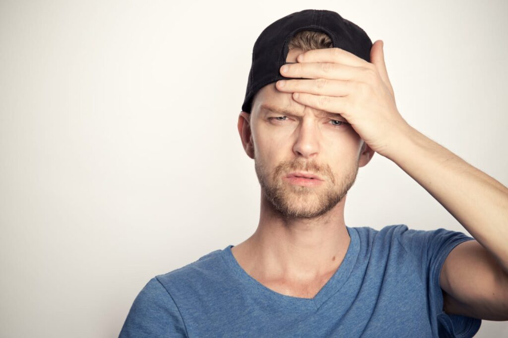 Homem jovem com expressão de dor e a mão na testa, representando sintomas de AVC.