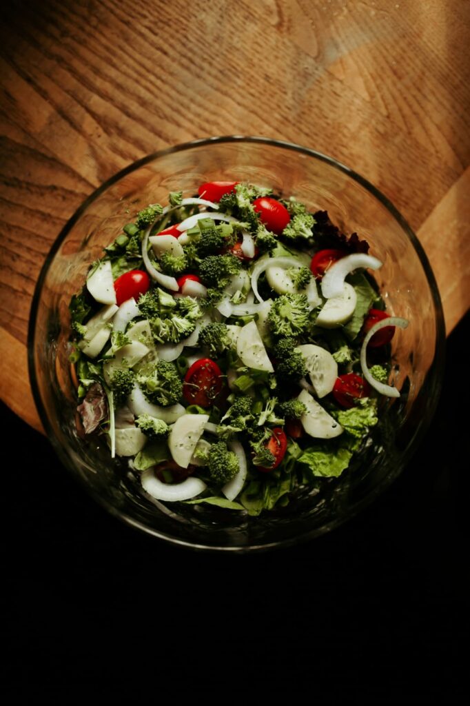 Tigela de salada fresca com brócolis, alface, tomate e cebola, fontes naturais de Vitamina K.