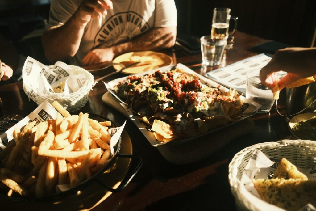Bandeja de bebidas alcoólicas em um bar ao lado de porções de comida, ilustrando o impacto do álcool no emagrecimento.
