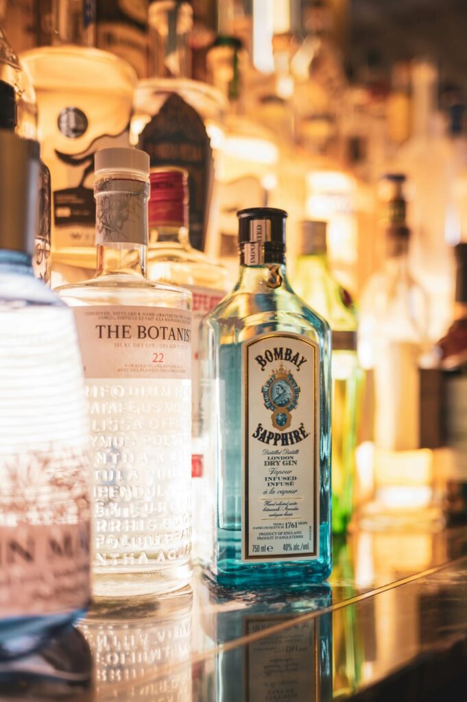 Prateleira com garrafas de bebidas alcoólicas, incluindo gin, representando o impacto do álcool no desenvolvimento da cirrose hepática.