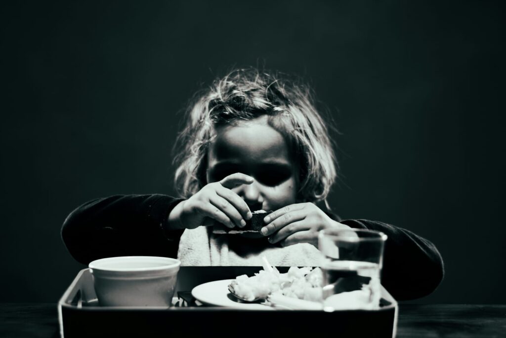 Criança com sinais de desnutrição se alimentando.