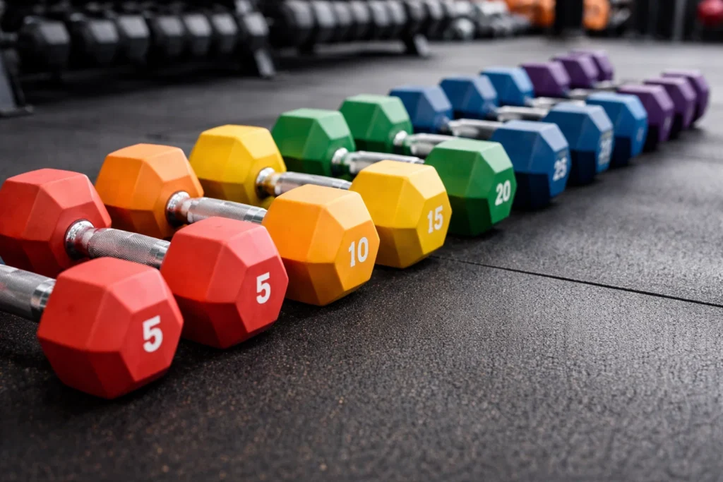 Halteres de diferentes pesos alinhados em uma academia, ilustrando intensidade de treino e a discussão sobre quando Exercício de mais faz mal.